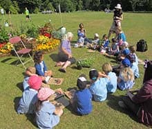 A group of children sitting on a lawn beside a display of flowers